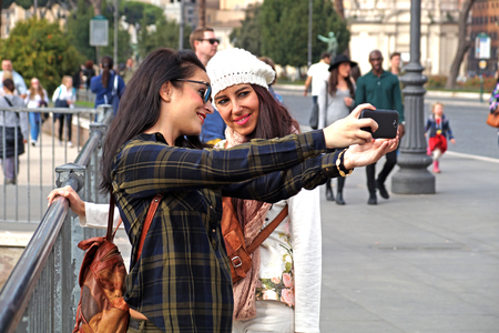 ROME, ITALY : Group of cheerful young friends on the beach taking photos using selfie stickのeditorial素材