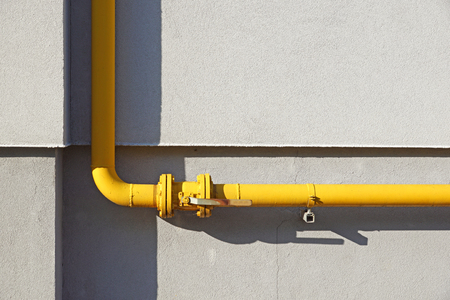 Yellow gas pipe in front of residential building wallの写真素材