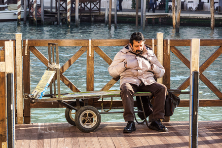 VENICE , ITALY -20 DECEMBER 2016 : An unidentified man relaxes on his waiting wagon customers asleep to rest .のeditorial素材