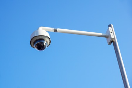 High tech overhead security camera with blue sky.