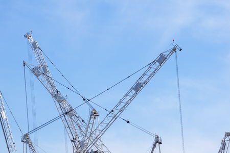 Tall white tower crane against bright blue skyの写真素材