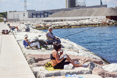 Venice , Italy 8 July 2017 : Tourists fish and relax on the dock at the entrance to the sea in Europeのeditorial素材