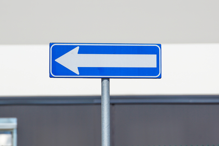 White one way traffic sign against industrial background .
