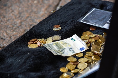 Hand throwing money in the old hat from a street artist, finance concept, selected focus, narrow...