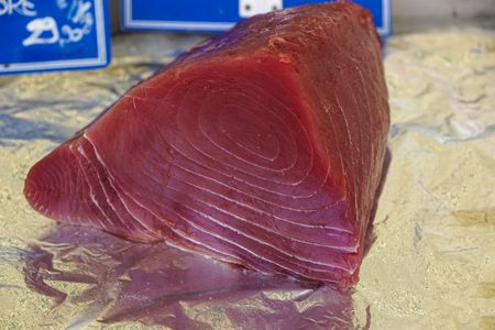 Fresh and raw big tuna fish was cut into pieces by the expert fishmonger for showing to the customer at the fresh and clean marketの写真素材