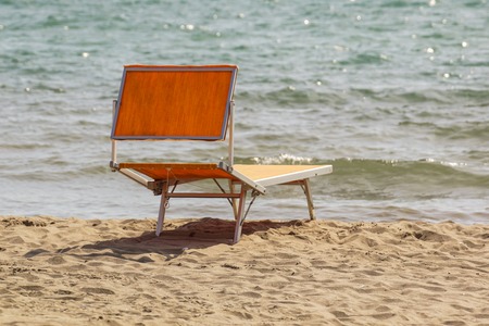 Bright chaise lounge on sand on seashore. Against background of seaの写真素材