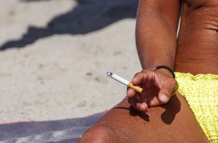 Smoking with cigarette butts ashtray on the sand on the beach and travel activityの写真素材