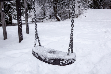 Empty swing in winter time with snow.の写真素材