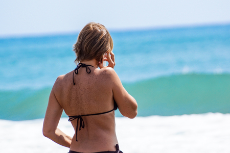 Landscape with the beautiful happy girl, talking on phone on a sea coastの写真素材