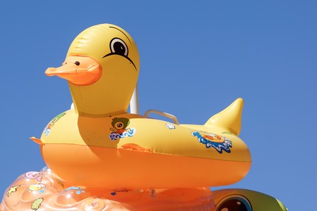 Inflatable ring player with soft wave of blue ocean on sandy beach. Background of travel in summer seasonの写真素材