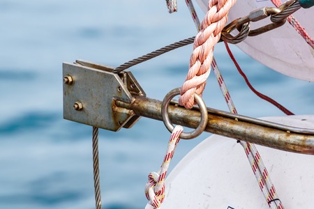 Steel rope and rusty hook on the back side of the sailing boat. Flag of Greece and historical castle...