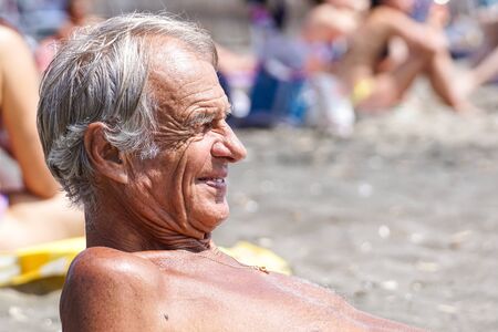 TUSCANY , ITALY 17 JULY 2018 : Side view of a contemplative casual senior man relaxing at the beachのeditorial素材