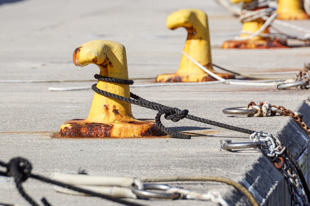 A mooring bollard entwined with a mooring rope. Moored ships at the port quayの写真素材
