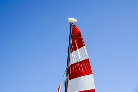 Sailing boat with red sail on a beachの写真素材