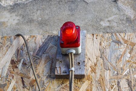 bright red construction lamp lit with fence in background on entrance of construction site .