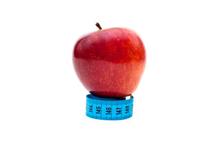 Organic apple and a tape measure over a white backroundの写真素材