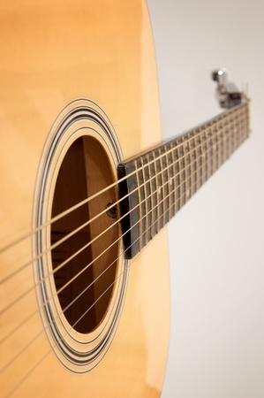 Detail of an yellow, wooden acoustic guitar over a white backgroundの写真素材