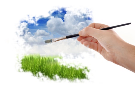 Male hand with pait brush painting a beautiful summer landscape with blue sky and cloudsの写真素材