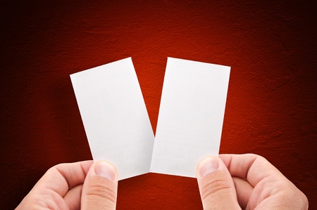 Hands holding empty business cards over grungy red backgroundの写真素材