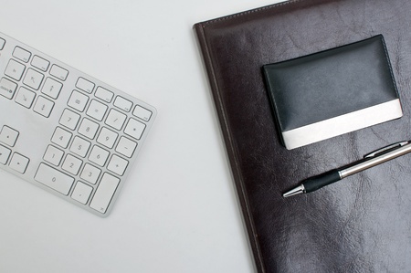 Office desk detail, a computer keyboard, agenda and a pen on a white table top. Business concept.の写真素材