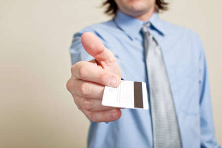 Business man presenting his credit card with shallow depth of field, focus on the card. Shopping and spending conceptの写真素材