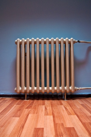 Heating radiator on purple wall in a room with laminated wooden floorの写真素材