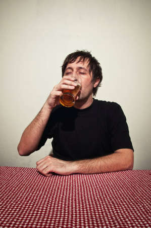 Drunk man at the pub table with a glass of cold, light beer.の写真素材
