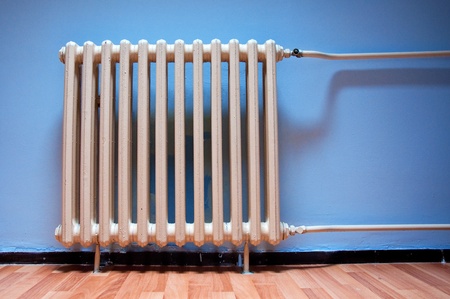 Heating radiator on purple wall in a room with laminated wooden floorの写真素材