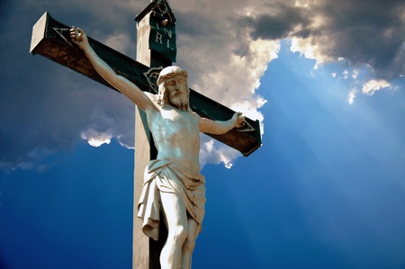 A statue of Jesus Christ crucified against dramatic skyの写真素材
