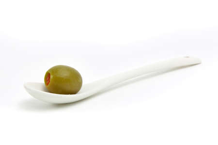 Green olive on a white ceramic spoonの写真素材