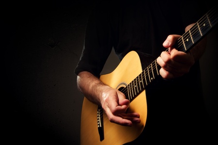 MAn is playing an acoustic guitar in low light environmentの写真素材