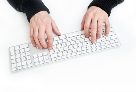Man is typing on computer keyboard on a white desktopの写真素材