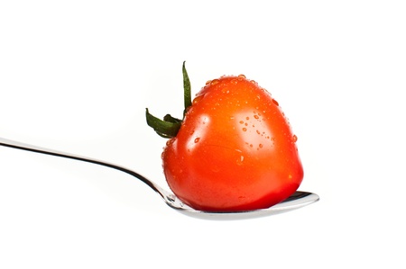 Single red heart-shaped tomato on a silver spoonの写真素材