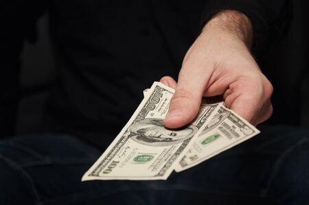 Close up of a male hand holding few US dollar bills