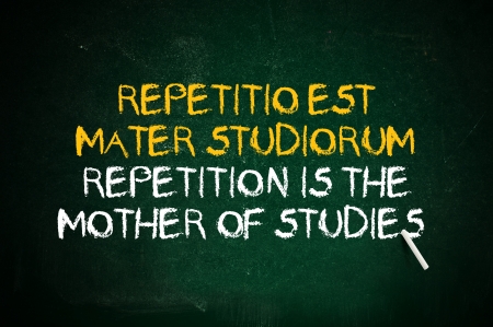 Repetition is the mother of studies. Latin quote handwritten with chalk on a green school board.の写真素材