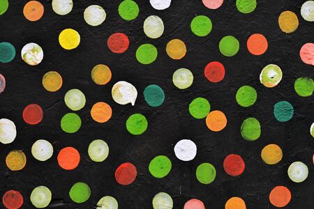 Abstract dotted background, colorful dots painted on the black wall 