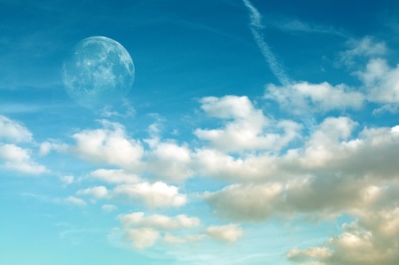 Beautiful fluffy white clouds in blue summer sky with visible moon. This cloudscape image is suitable as a background for your design.の写真素材