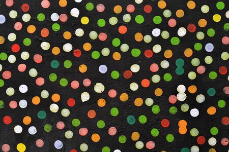 Abstract dotted background, colorful dots painted on the black wall.