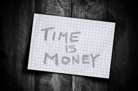 Reminder note Time is money on a piece of paper on a old wooden bacground.