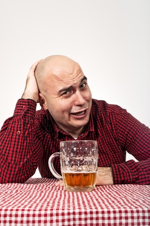 Young adult bald man drinks beer from a jugの写真素材