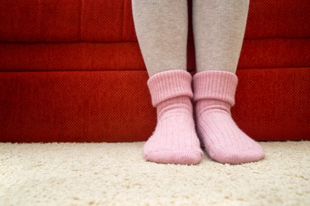 Female legs wearing beautiful warm pink woolen socks at home.の写真素材