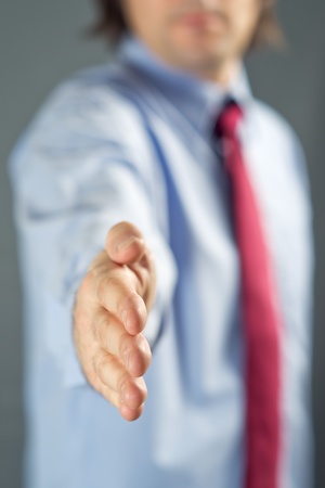 Businessman in blue shirt with open hand for a friendly handshake. Greeting or seal a deal concept.の写真素材