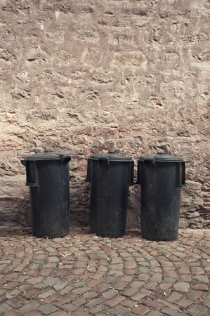 Three black plastic garbage bins on the streetの写真素材