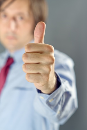 Businessman showing thumb up, satisfied pleased employer or manager concept. Ok, approval, recognition concept.の写真素材