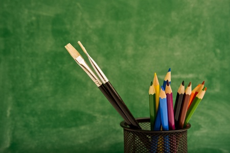 Colour pencils in pencil box, green chalkboard in backgroundの写真素材