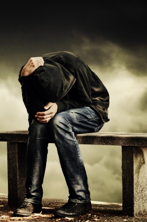 Man with problems  Man in hood with hands on his head sitting on the concrete bench  Drug addict concept の写真素材