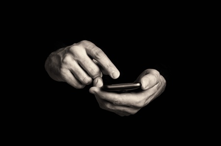 Man typing text message on his smartphone, focus on hands and the phone device.