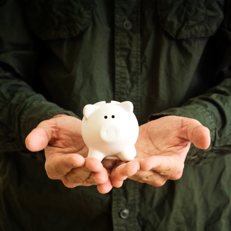 Piggy coin bank in cupped hands of man.の写真素材