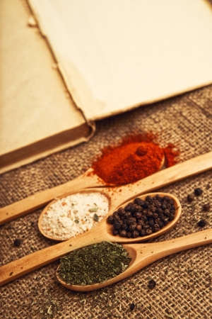 Spices. Food ingredients on wood spoons with open book on kitchen table.の写真素材