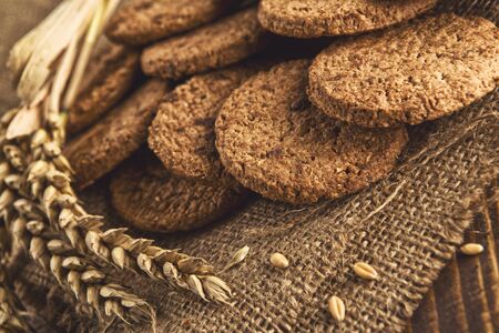 Chocolate chip cookies. Delicious and fresh cookies on wooden table with some wheat ears and grains.